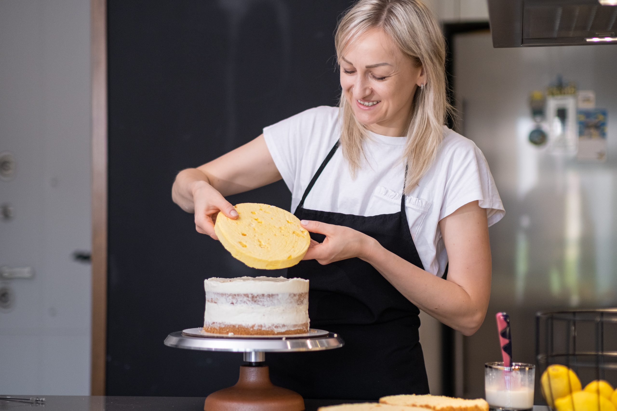 satisfied-blonde-woman-connecting-fresh-cake-layer-2024-12-01-11-36-23-utc-scaled